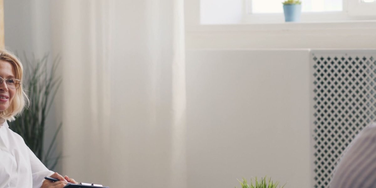 A mental health professional conducting a detailed interview with a client in a supportive therapy setting.