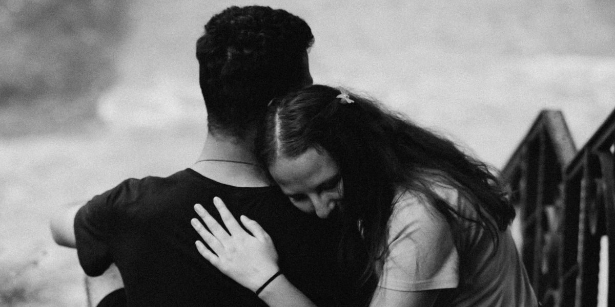 A couple sitting closely, looking supportive, symbolizing the importance of addressing addiction and relationship problems together.
