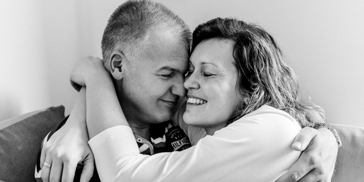 A couple sitting distant from each other in a living room, illustrating the emotional distance and conflict caused by addiction.