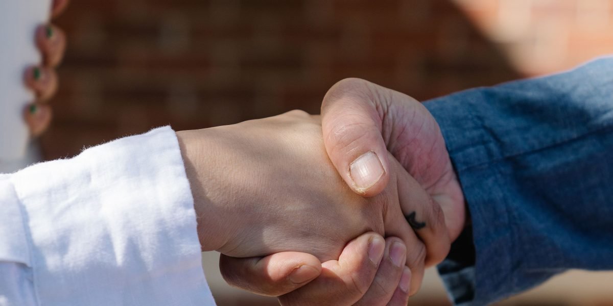 Two professionals shaking hands, symbolizing successful collaboration and combined effort towards a goal.